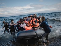 Volunteers help migrants embark from the dinghy they have arrived on, in Lesbos, on September 30, 2015.  (