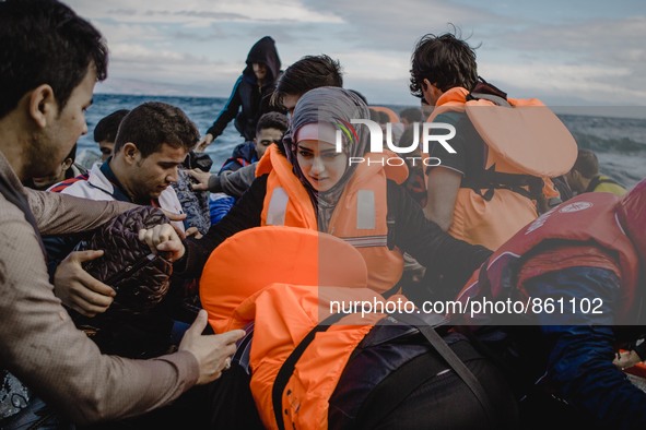 A Syrian women is helped by other migrants onto the shore on the Greek island of Lesbos, on September 30, 2015.  