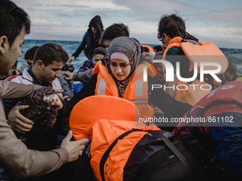 A Syrian women is helped by other migrants onto the shore on the Greek island of Lesbos, on September 30, 2015.  (