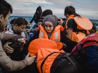 A Syrian women is helped by other migrants onto the shore on the Greek island of Lesbos, on September 30, 2015.  (