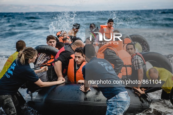 Volunteers help migrants embark from the dinghy they have arrived on, in Lesbos, on September 30, 2015.  