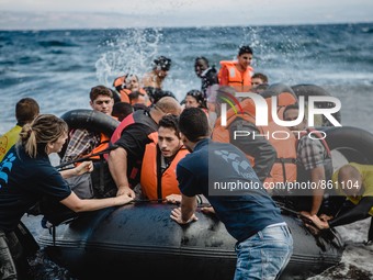 Volunteers help migrants embark from the dinghy they have arrived on, in Lesbos, on September 30, 2015.  (