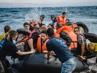 Volunteers help migrants embark from the dinghy they have arrived on, in Lesbos, on September 30, 2015.  (