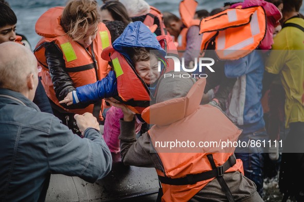 A child is passed off of the boat she crossed the sea on and into her mother’s arms, in Lesbos, on September 30, 2015.  