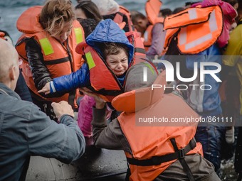 A child is passed off of the boat she crossed the sea on and into her mother’s arms, in Lesbos, on September 30, 2015.  (