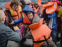 A child is passed off of the boat she crossed the sea on and into her mother’s arms, in Lesbos, on September 30, 2015.  (