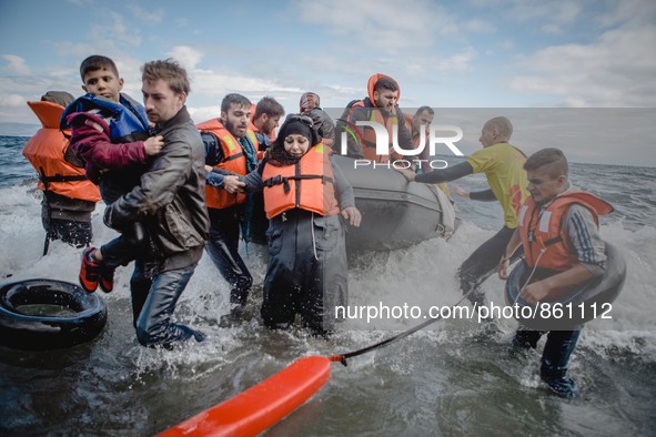 Volunteers help migrants embark from the dinghy they have arrived on, on September 30, 2015.  