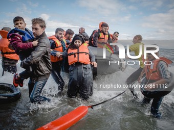 Volunteers help migrants embark from the dinghy they have arrived on, on September 30, 2015.  (