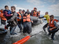 Volunteers help migrants embark from the dinghy they have arrived on, on September 30, 2015.  (