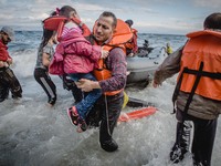 A father carries his daughter off their boat which was stranded in the water for five hours without a motor, in Lesbos, on September 30, 201...