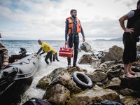 A migrant stands with his lifejacket and personal belongings after arriving on the Greek shore, in Lesbos, on September 30, 2015.  (