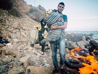 A volunteer carries a Syrian child wrapped in a thermal blanket and regular blanket off the beach in Lesbos, Greece, on September 30, 2015....