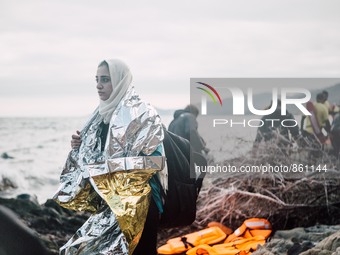 A women wrapped in a thermal blanket looks back at the sea she just crossed from Turkey to Greece, on September 30, 2015.  (