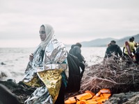 A women wrapped in a thermal blanket looks back at the sea she just crossed from Turkey to Greece, on September 30, 2015.  (