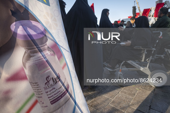 Iranian people stand next to a banner with an image of the Iranian Noora new coronavirus disease (COVID-19) vaccine during a ceremony to mar...