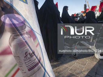 Iranian people stand next to a banner with an image of the Iranian Noora new coronavirus disease (COVID-19) vaccine during a ceremony to mar...