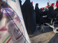 Iranian people stand next to a banner with an image of the Iranian Noora new coronavirus disease (COVID-19) vaccine during a ceremony to mar...