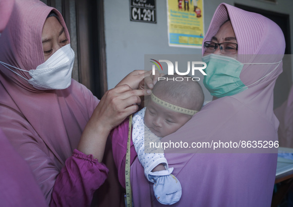 A sleep baby is measured body development by medical officers, during the BIAS (National Child Immunization Month) program at the Integrated...