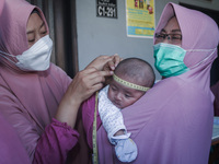 A sleep baby is measured body development by medical officers, during the BIAS (National Child Immunization Month) program at the Integrated...