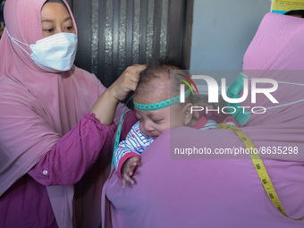 A sleep baby is measured body development by medical officers, during the BIAS (National Child Immunization Month) program at the Integrated...