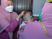 A sleep baby is measured body development by medical officers, during the BIAS (National Child Immunization Month) program at the Integrated...