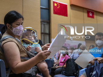 A women holding a baby who is waiting in line to get a jab of the Sinova CoronaVac vaccine made by Sinovac Biotech Ltd. a Chinese biopharmac...