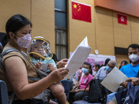 A women holding a baby who is waiting in line to get a jab of the Sinova CoronaVac vaccine made by Sinovac Biotech Ltd. a Chinese biopharmac...