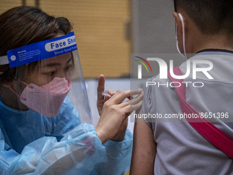 A women wearing a face shield and PPE administering a jab of the Sinova CoronaVac vaccine made by Sinovac Biotech Ltd. a Chinese biopharmace...