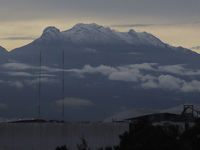 View of the Iztaccihuatl volcano (also known as the Sleeping Woman), during dawn and cloudy skies in Mexico City due to the monsoon that gen...