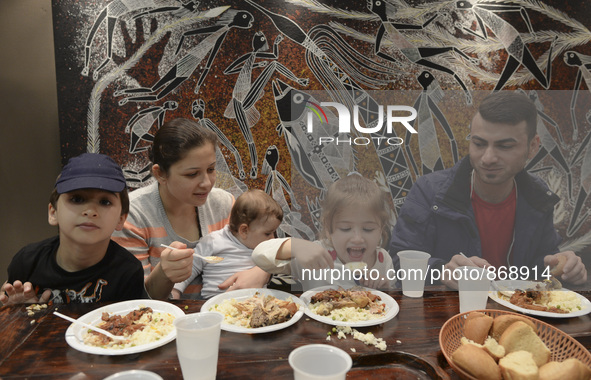 A Syrian family of refugees having a meal in the Aspa Boomerang Restaurant, as the owner Michael Pastrikos, helped by his family members, hi...