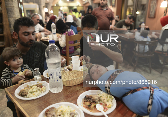 Families of refugees having a meal in the Aspa Boomerang Restaurant, as the owner Michael Pastrikos, helped by his family members, his staff...