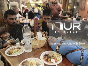 Families of refugees having a meal in the Aspa Boomerang Restaurant, as the owner Michael Pastrikos, helped by his family members, his staff...