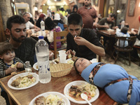 Families of refugees having a meal in the Aspa Boomerang Restaurant, as the owner Michael Pastrikos, helped by his family members, his staff...