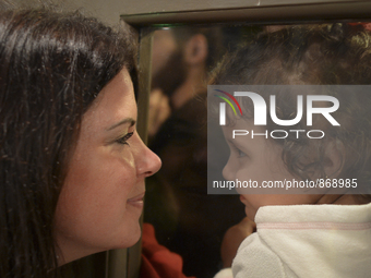 A Canadian volunteer looks from inside of the restaurant at a refugee's child, as many families are awaiting to enter to the Aspa Boomerang...