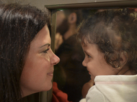 A Canadian volunteer looks from inside of the restaurant at a refugee's child, as many families are awaiting to enter to the Aspa Boomerang...