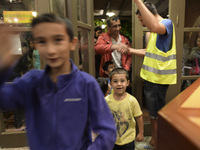 Happy young refugees enter to the Aspa Boomerang Restaurant, as the owner Michael Pastrikos, helped by his family members, his staff and man...