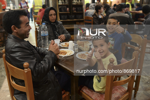 Happy family from Afganistan having their evening meal together at the Aspa Boomerang Restaurant, as the owner Michael Pastrikos, helped by...