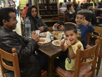 Happy family from Afganistan having their evening meal together at the Aspa Boomerang Restaurant, as the owner Michael Pastrikos, helped by...