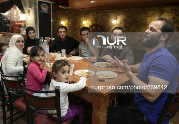 Happy family from Syria having their evening meal together at the Aspa Boomerang Restaurant, as the owner Michael Pastrikos, helped by his f...