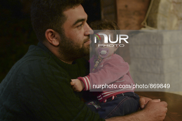 A young refugee with his daughter awaiting to enter to the Aspa Boomerang Restaurant, as the owner Michael Pastrikos, helped by his family m...