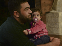 A young refugee with his daughter awaiting to enter to the Aspa Boomerang Restaurant, as the owner Michael Pastrikos, helped by his family m...