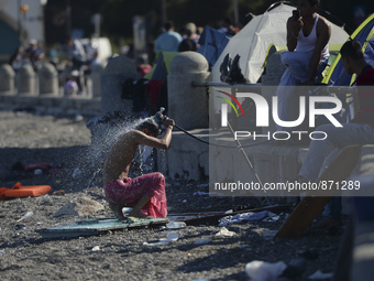 A migrant washes himself in front of the main Police station, as awaiting in Kos harbour to be processed by the Greek police and given paper...