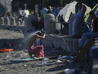 A migrant washes himself in front of the main Police station, as awaiting in Kos harbour to be processed by the Greek police and given paper...