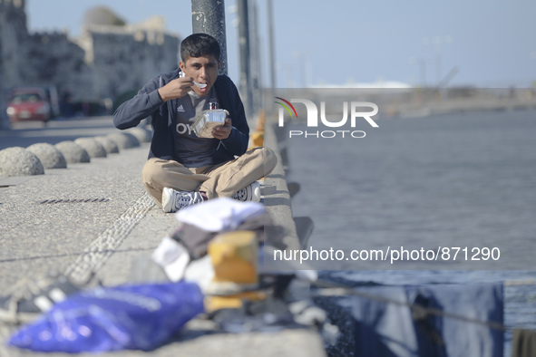 A migrant enjoys a meal he received from local volunteers, as awaiting in Kos harbour to be processed by the Greek police and given paperwor...