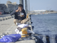 A migrant enjoys a meal he received from local volunteers, as awaiting in Kos harbour to be processed by the Greek police and given paperwor...