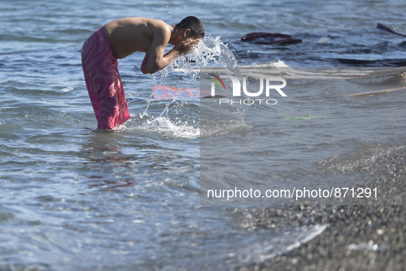 A migrant takes a bath in front of the main Police station, as awaiting in Kos harbour to be processed by the Greek police and given paperwo...