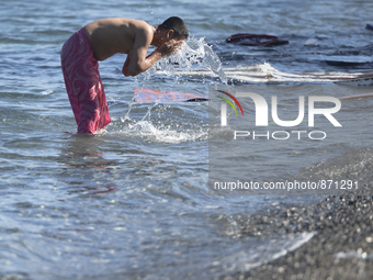 A migrant takes a bath in front of the main Police station, as awaiting in Kos harbour to be processed by the Greek police and given paperwo...