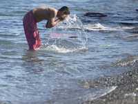 A migrant takes a bath in front of the main Police station, as awaiting in Kos harbour to be processed by the Greek police and given paperwo...