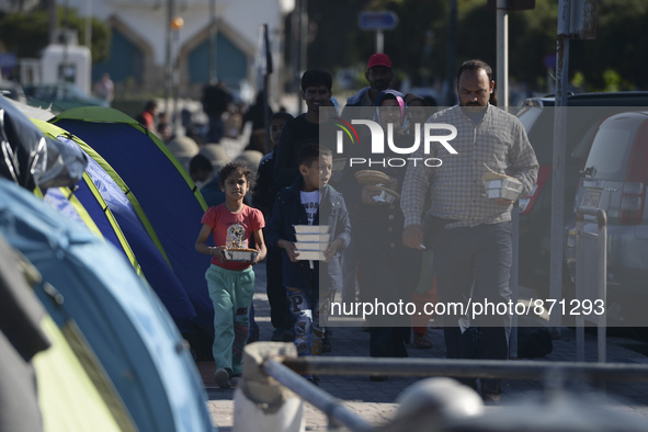 A family of migrants pictured in Kos harbour after they received a hot meals from local volunteers, as awaiting to be processed by the Greek...