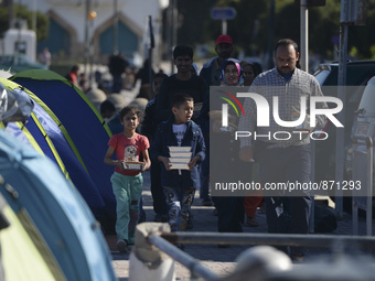 A family of migrants pictured in Kos harbour after they received a hot meals from local volunteers, as awaiting to be processed by the Greek...